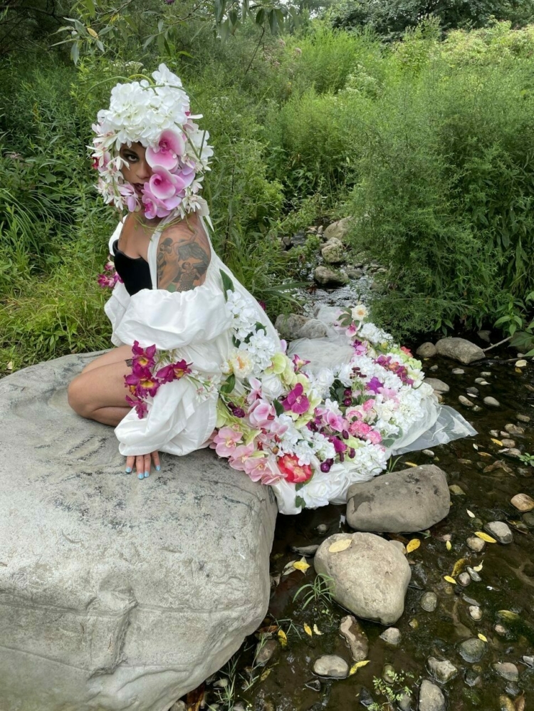 A person near a small river covered in flowers.
