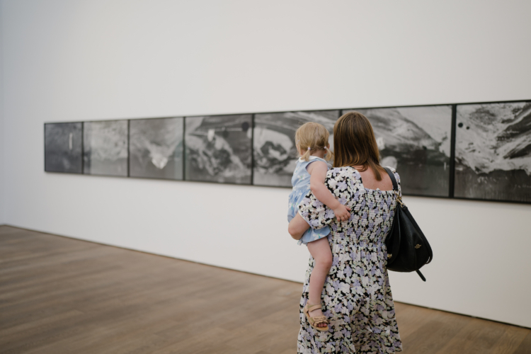 A mother holding her child in front of a series of black and white images.