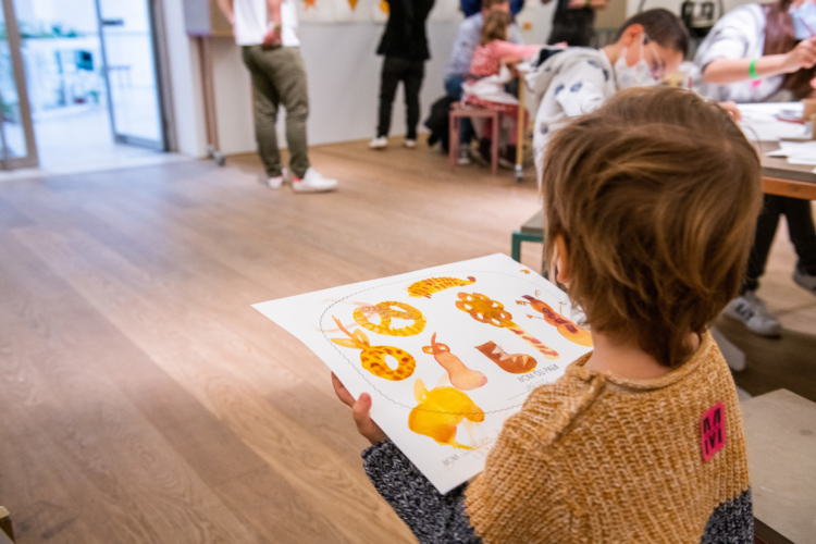 A child carrying a drawing of breads in different sizes and shapes.
